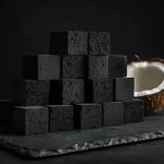 Coconut charcoal cubes premium grade stacked on dark surface with coconut shell prop